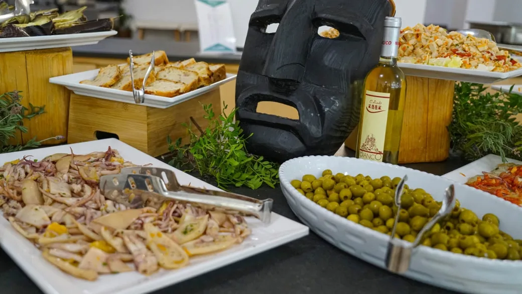 Dettaglio del buffet con frutti di mare, olive e maschera sarda
