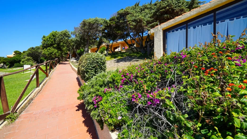Vialetto pedonale fiorito tra giardini e cottage del resort