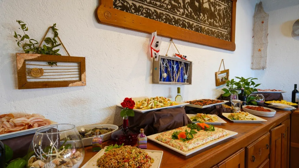 Buffet di antipasti e piatti sardi con decorazioni tradizionali alle pareti