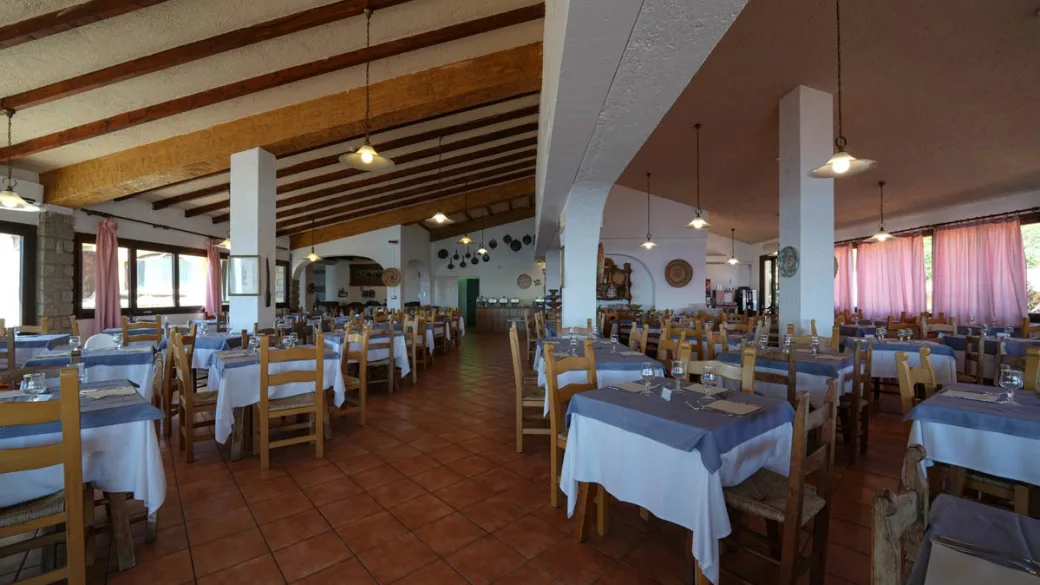 Ampia sala ristorante con travi in legno, colonne bianche e numerosi tavoli