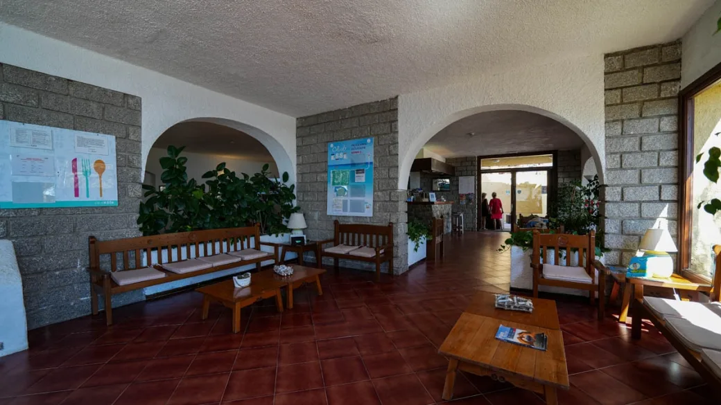 Hall reception con archi in pietra, divani in legno e piante verdi