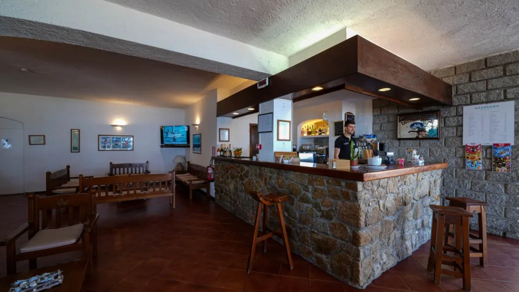 Bar interno con bancone in pietra, sgabelli e area relax