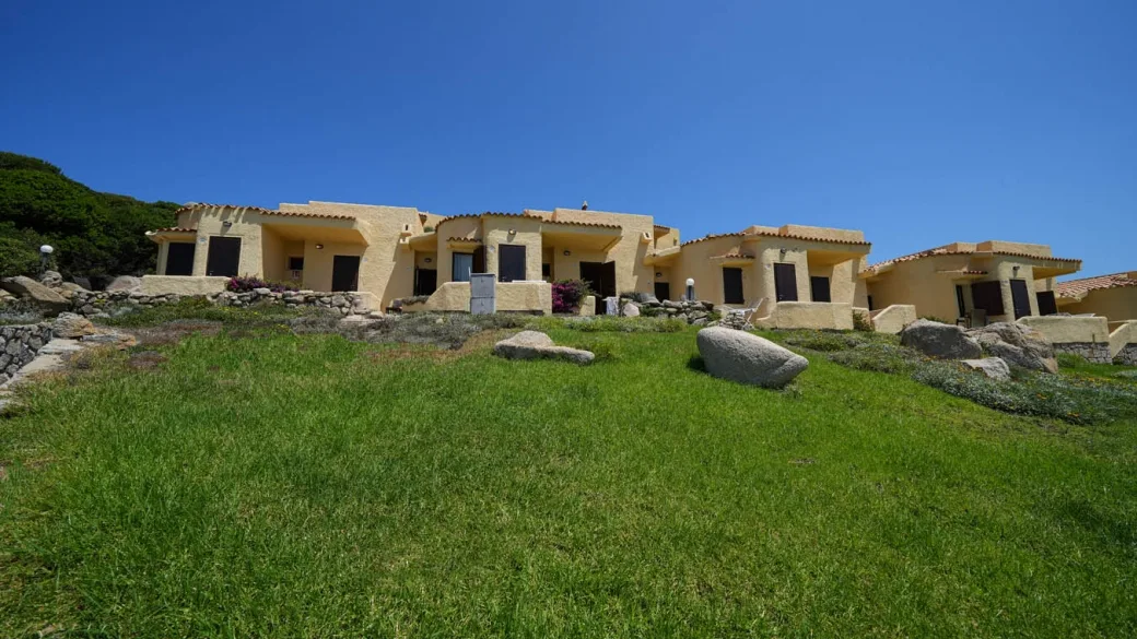 Cottage in stile sardo con giardino verde e cielo azzurro