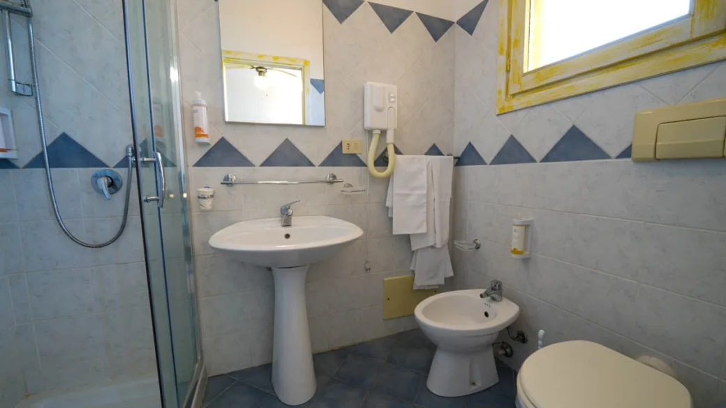 Bagno con doccia, lavabo, bidet e decorazioni a triangoli blu