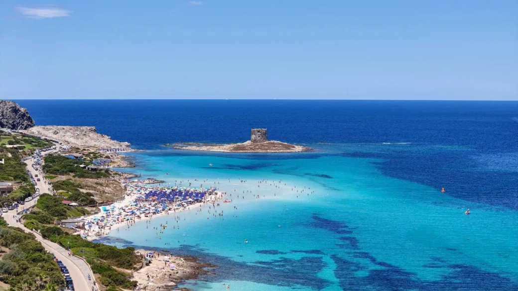 Panoramica della spiaggia della Pelosa con torre, ombrelloni e mare turchese