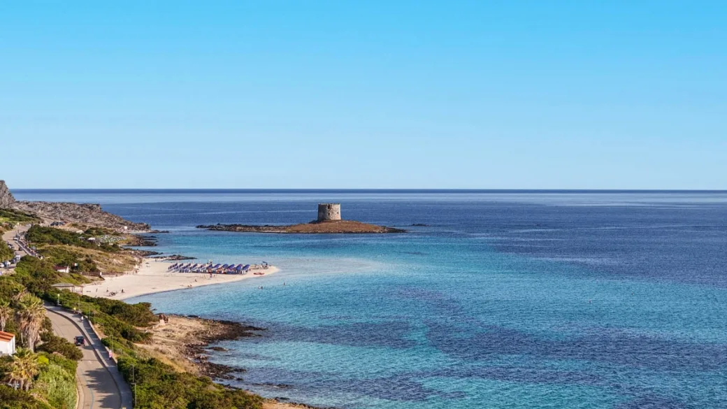 Vista della costa con spiaggia, torre e mare azzurro all'orizzonte