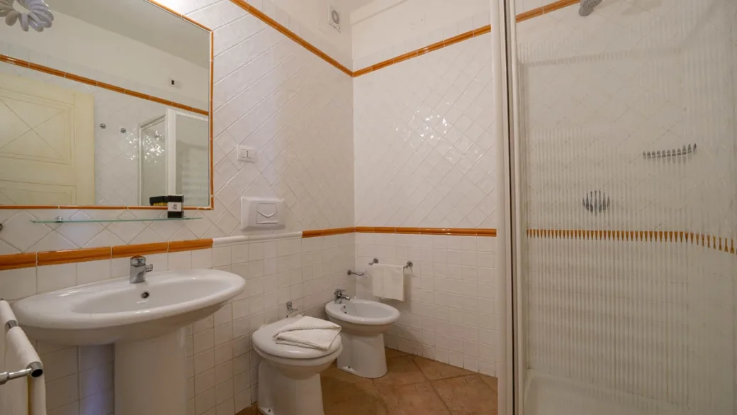Bagno della camera con doccia, lavabo, bidet e dettagli arancioni