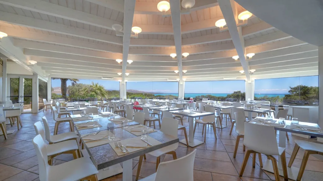 Sala ristorante con soffitto bianco a travi e ampie vetrate sul mare