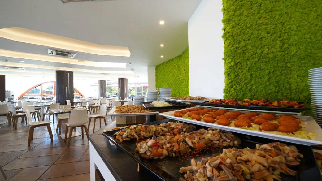 Buffet del ristorante con piatti caldi e parete verde decorativa