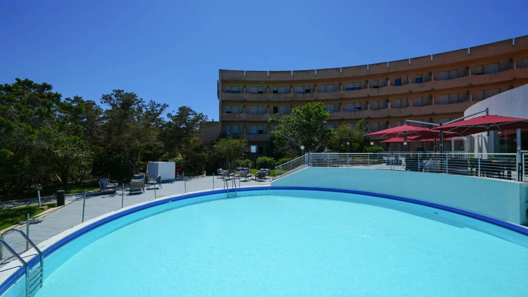 Piscina circolare con terrazza, lettini e ombrelloni rossi