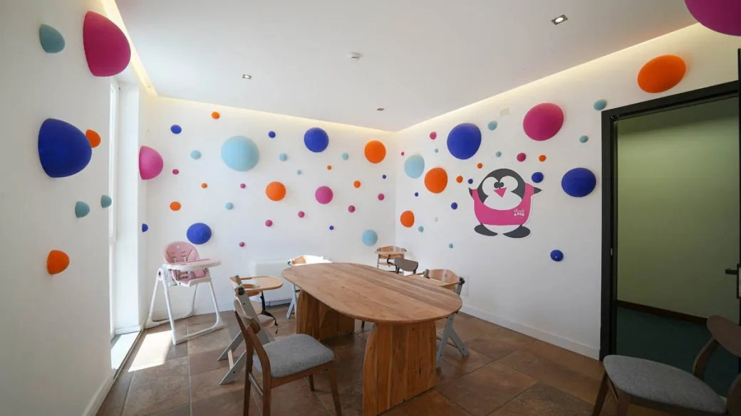 Sala per bambini con decorazioni a pois, tavolo in legno e seggioloni