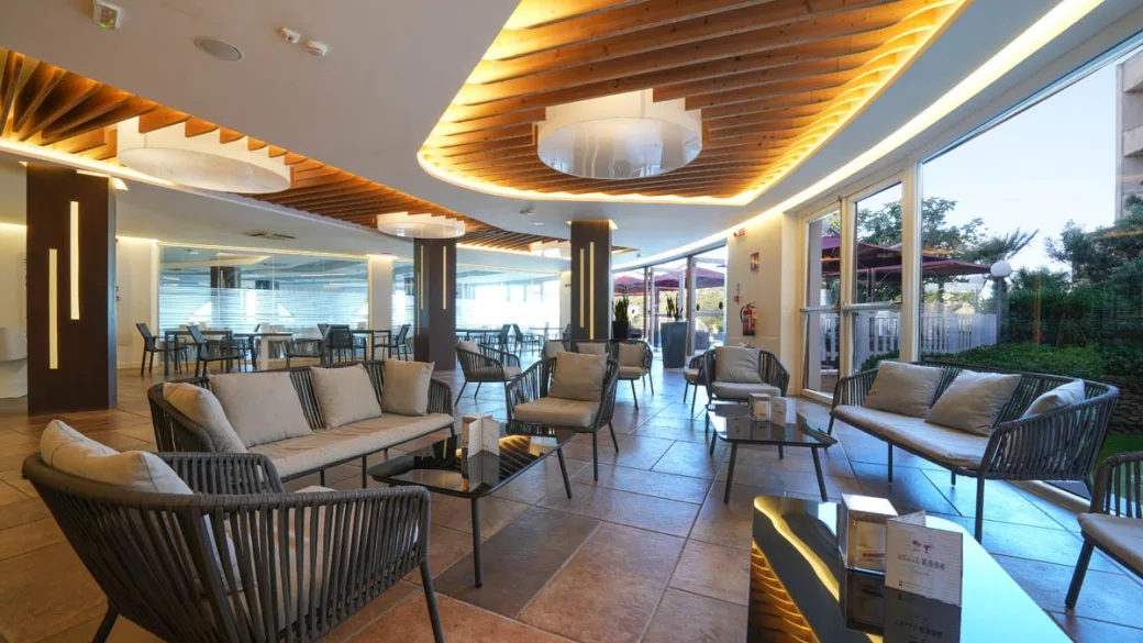 Sala lounge interna con divani, poltrone e soffitto in legno
