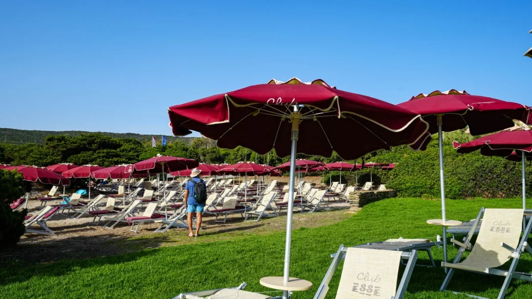 Area relax con lettini e ombrelloni rossi su prato verde