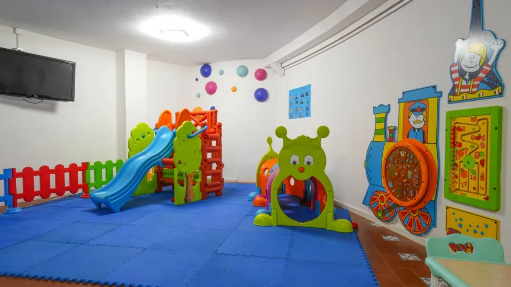 Sala giochi per bambini con scivolo, decorazioni colorate e TV