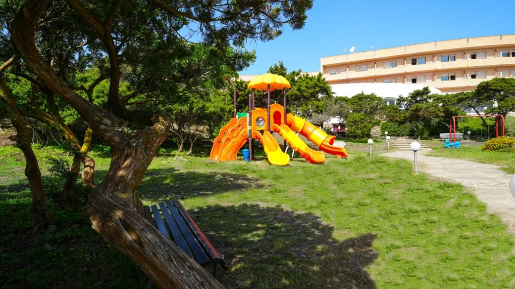 Area giochi per bambini con scivolo nel giardino dell'hotel