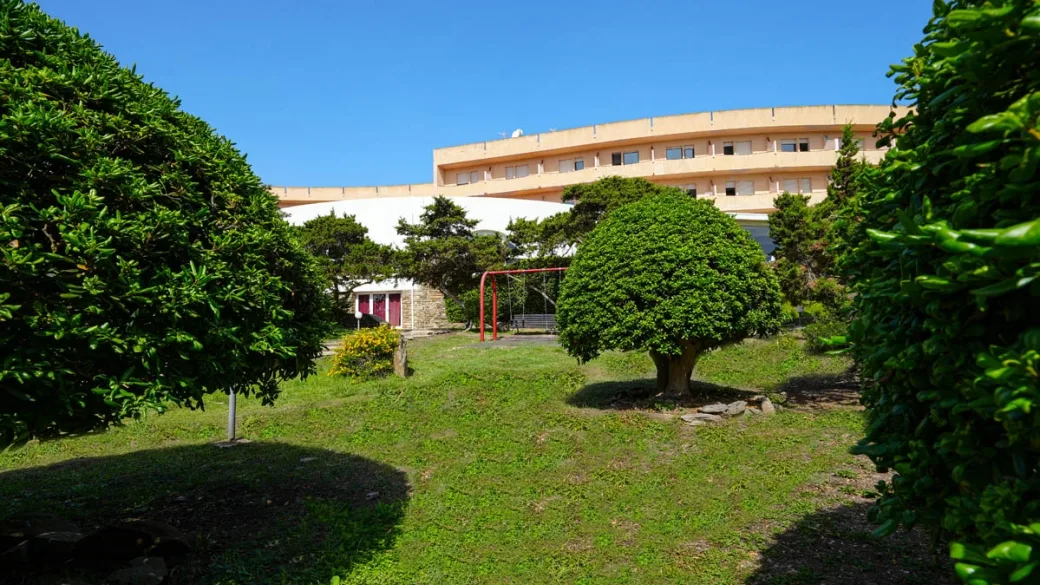 Giardino verde con alberi e area giochi davanti all'edificio dell'hotel
