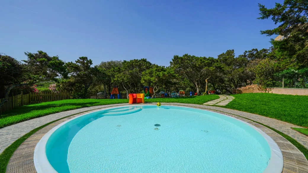 Piscina per bambini circolare circondata da prato verde e alberi