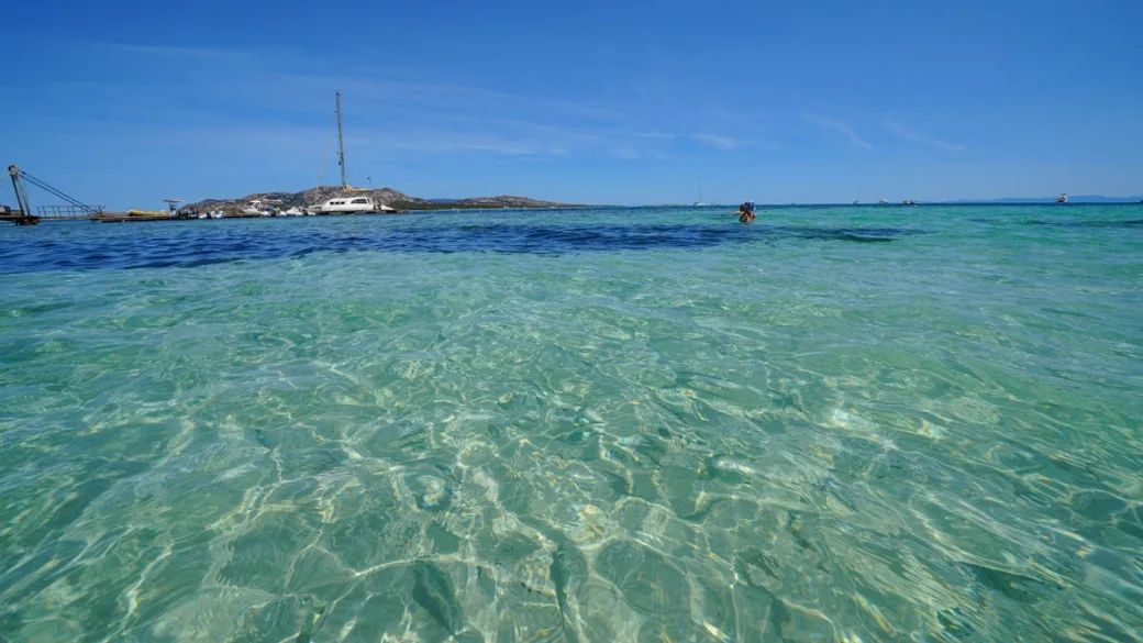 Acqua di mare limpida e trasparente con pontile e barche all'orizzonte