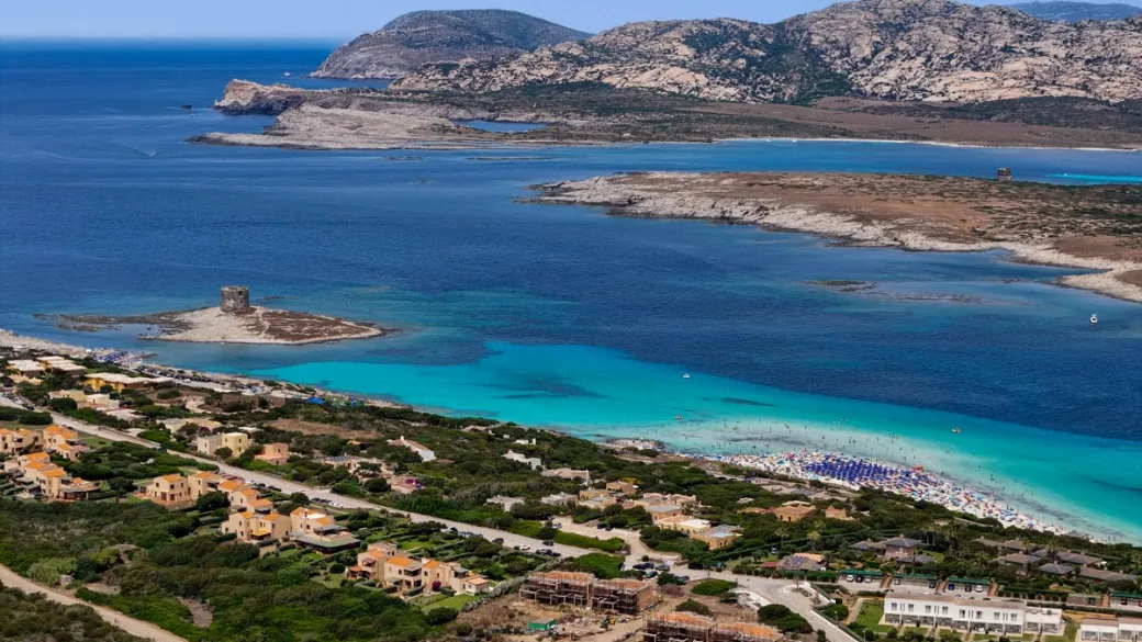 Panorama della costa con torre, spiaggia e abitazioni immerse nel verde