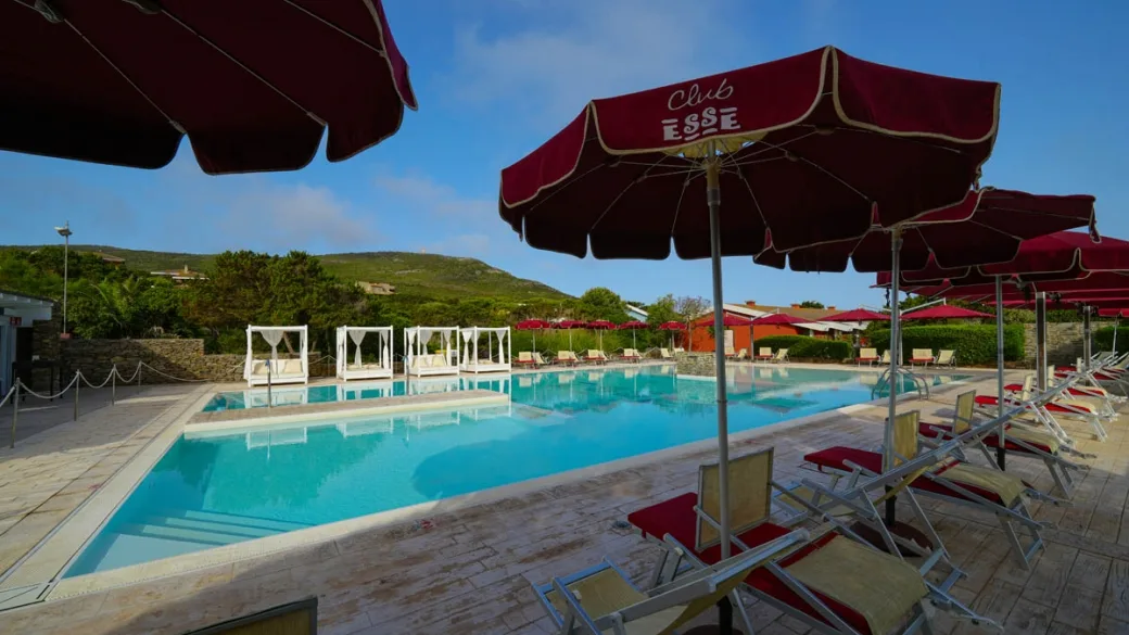 Piscina del Club Esse con lettini, ombrelloni rossi e colline sullo sfondo