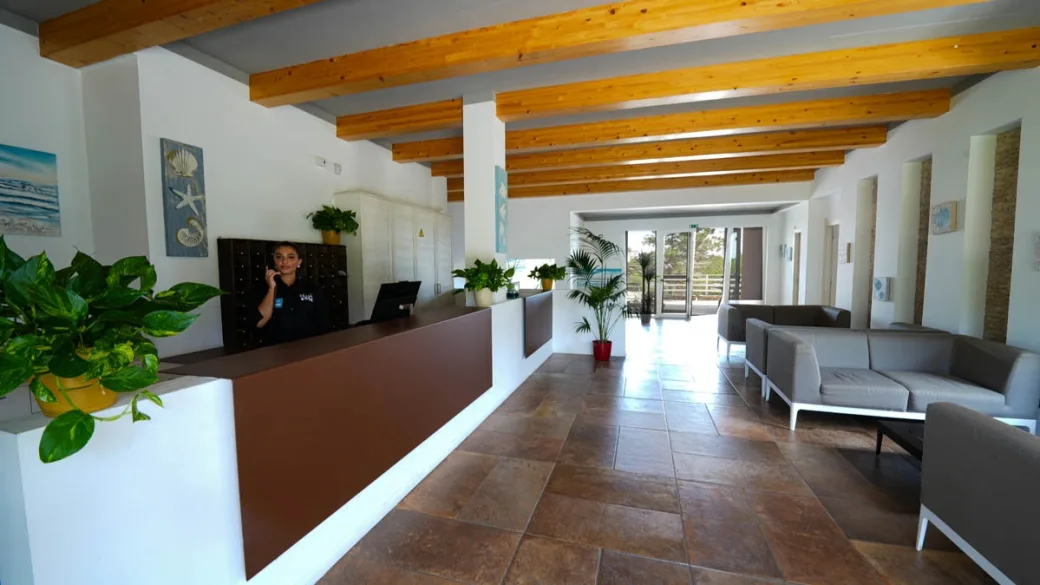 Reception dell'hotel con travi in legno, divani e piante verdi