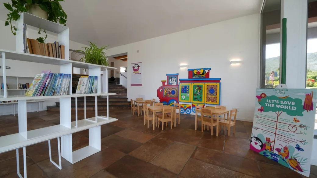 Area giochi per bambini con tavolini, libreria e giocattoli colorati