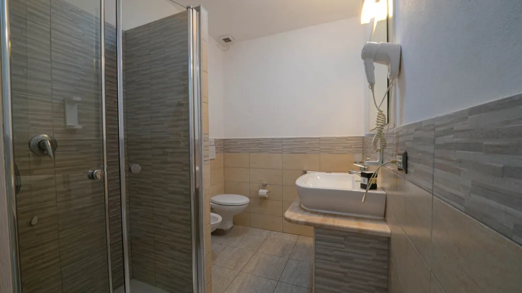 Bagno moderno con doccia, lavabo e rivestimenti in beige e grigio