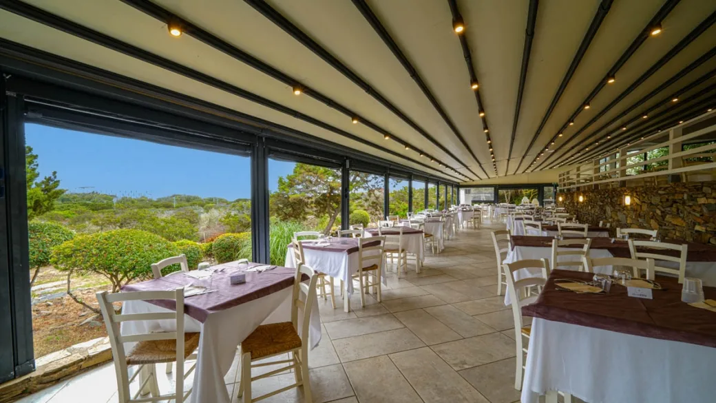 Ristorante con vetrate panoramiche e tavoli apparecchiati vista verde