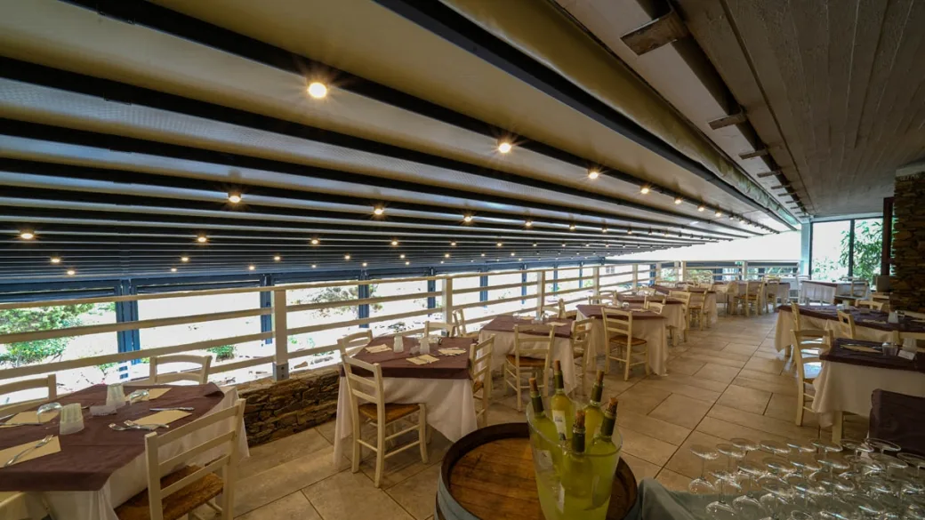 Sala ristorante con tavoli apparecchiati e bottiglie di vino in primo piano
