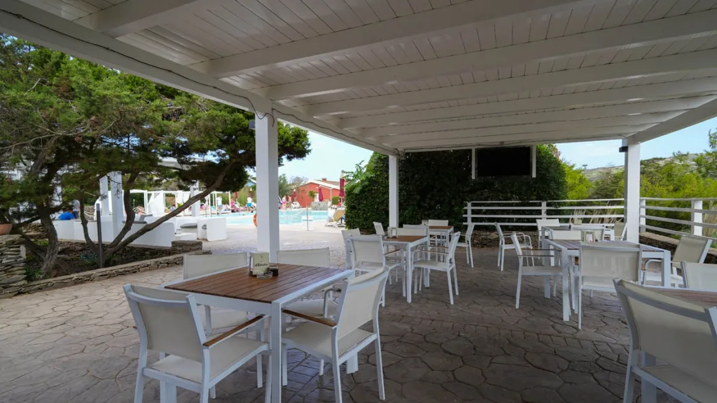 Terrazza esterna coperta con tavoli e sedie bianche vicino alla piscina