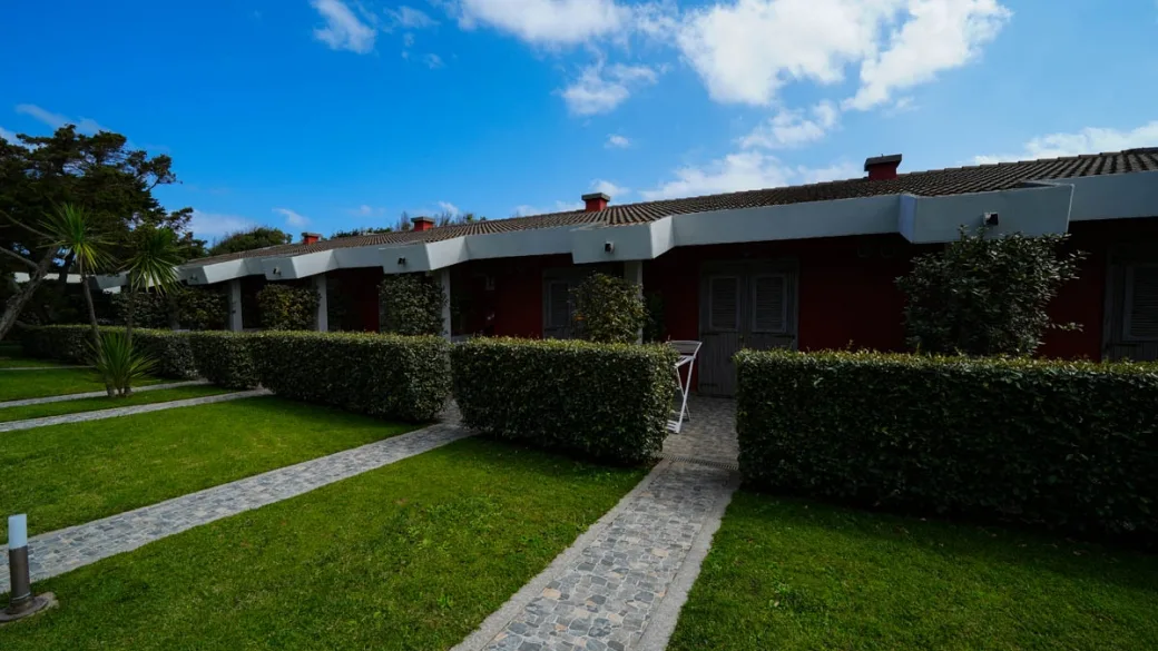 Esterno delle camere in edificio rosso con giardino e siepi curate