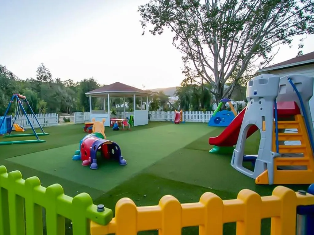 Parco giochi per bambini con scivoli, altalene e giochi colorati su prato verde