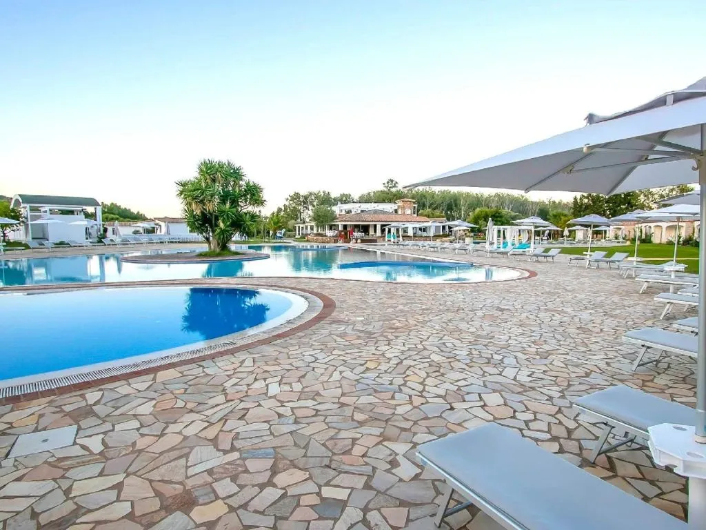 Piscine curve con pavimentazione in pietra, ombrelloni e lettini al crepuscolo
