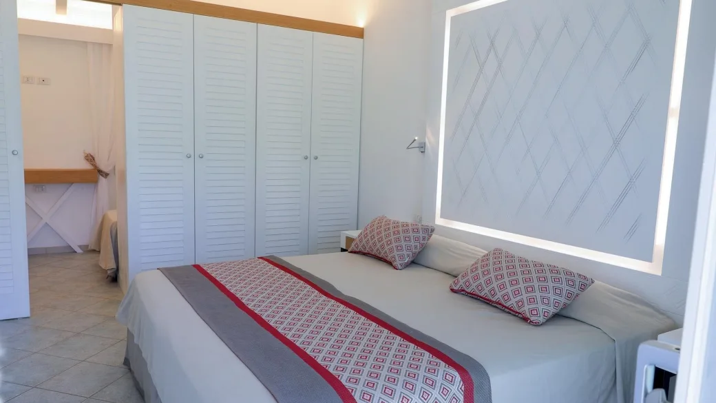 Camera con letto matrimoniale, armadio bianco e testiera illuminata