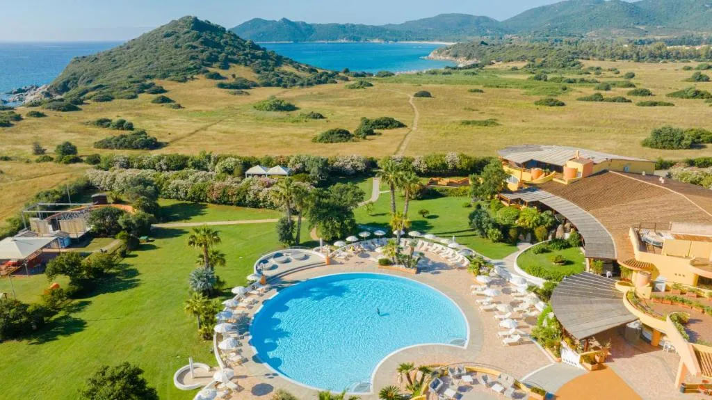 Vista aerea del resort con piscina rotonda, giardini e mare sullo sfondo