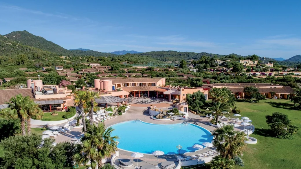 Veduta aerea del resort con grande piscina circolare e colline verdi