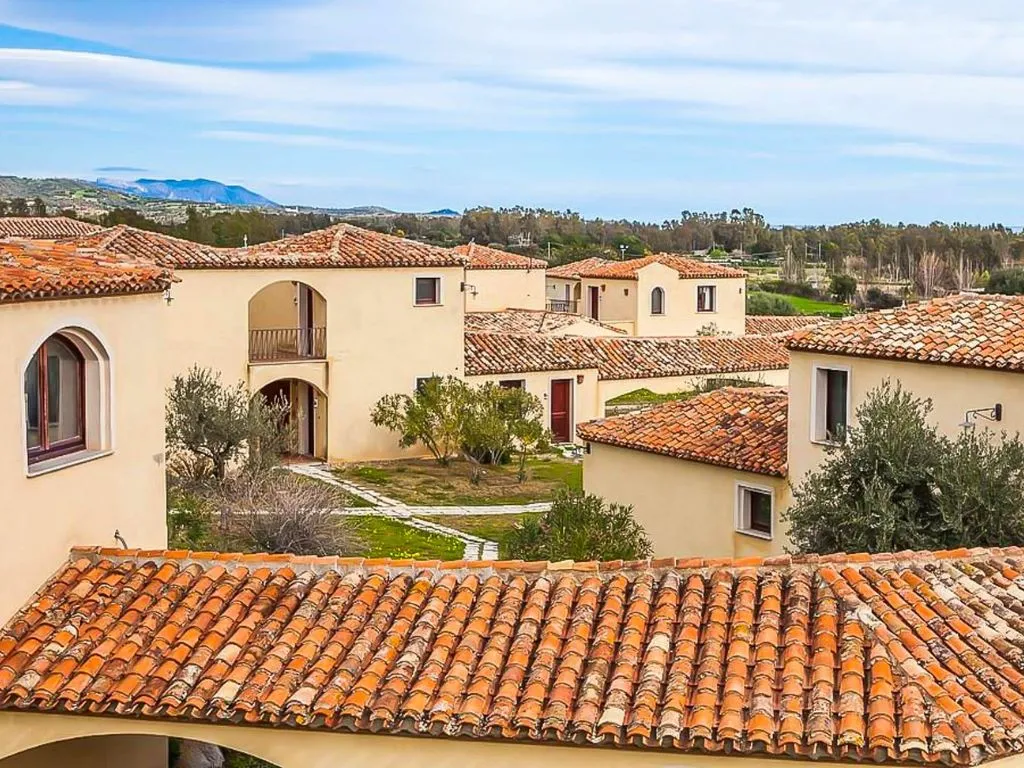 Vista sui tetti in coccio delle ville del resort con colline e cielo sullo sfondo
