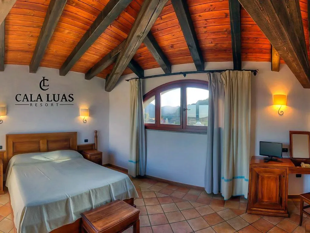Camera con soffitto in legno a vista, travi, letto matrimoniale e finestra ad arco