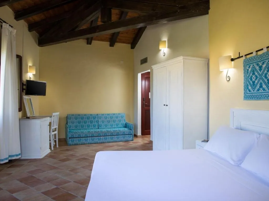 Camera spaziosa con soffitto in travi di legno, divano azzurro, armadio bianco e letto