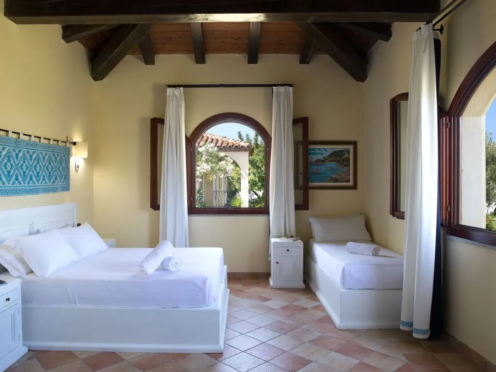 Camera luminosa con letto matrimoniale e singolo, soffitto in legno e finestre ad arco