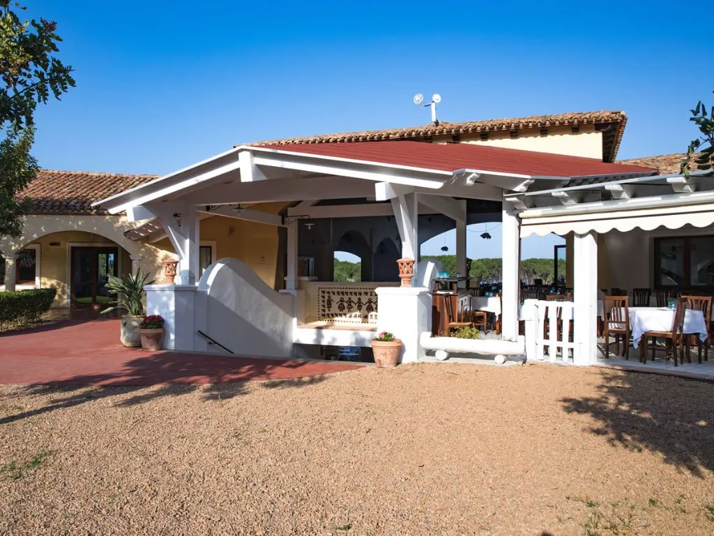 Edificio del ristorante con tettoia rossa, veranda e giardino verde curato