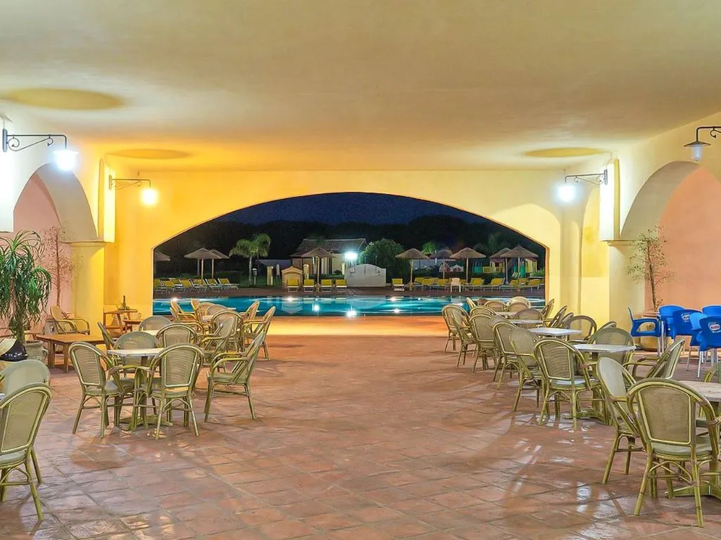 Area ristorante coperta con archi affacciata sulla piscina illuminata di sera