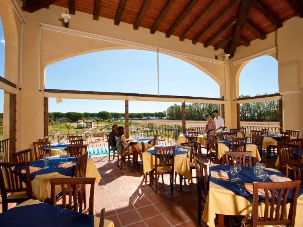 Terrazza ristorante con tavoli apparecchiati in blu e giallo e vista sulla campagna