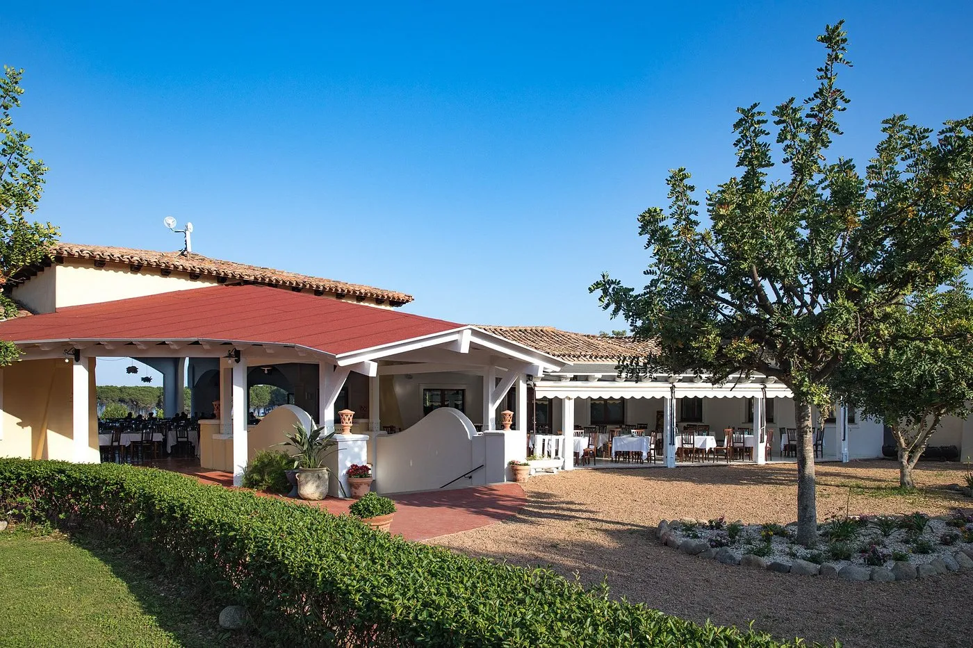 Ristorante all'aperto del resort con tettoia, giardino curato e vista sulla campagna