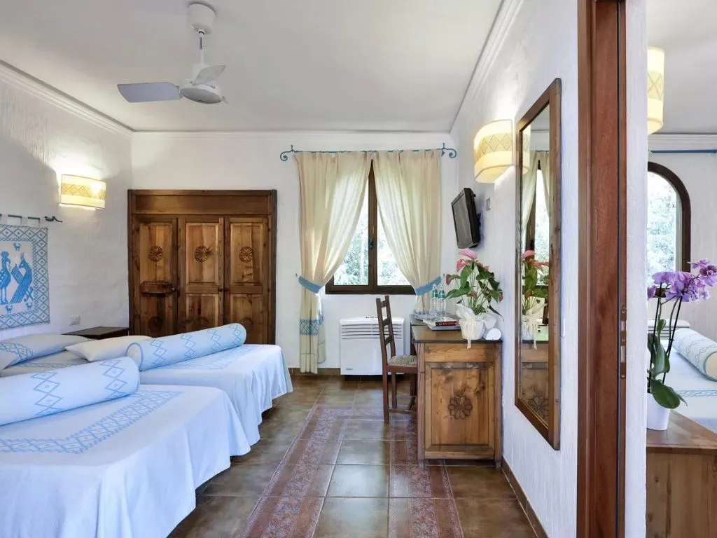 Camera con letti, ventilatore a soffitto, arredi in legno e decorazioni floreali