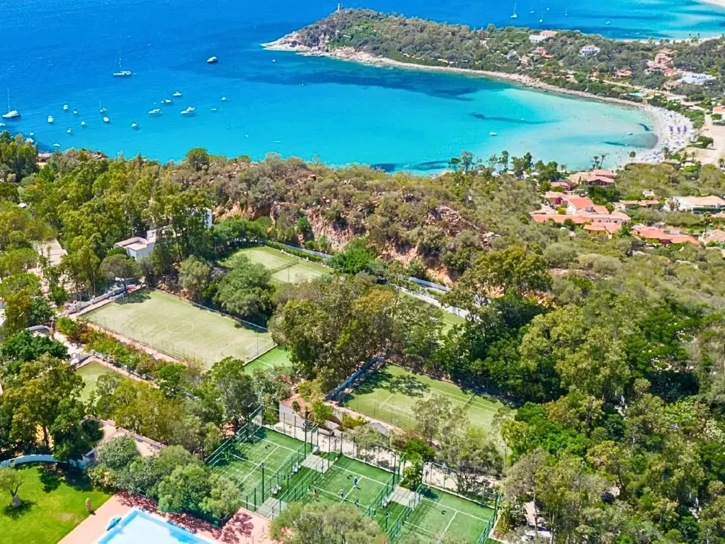 Vista aerea dei campi sportivi immersi nel verde con la baia dal mare turchese sullo sfondo