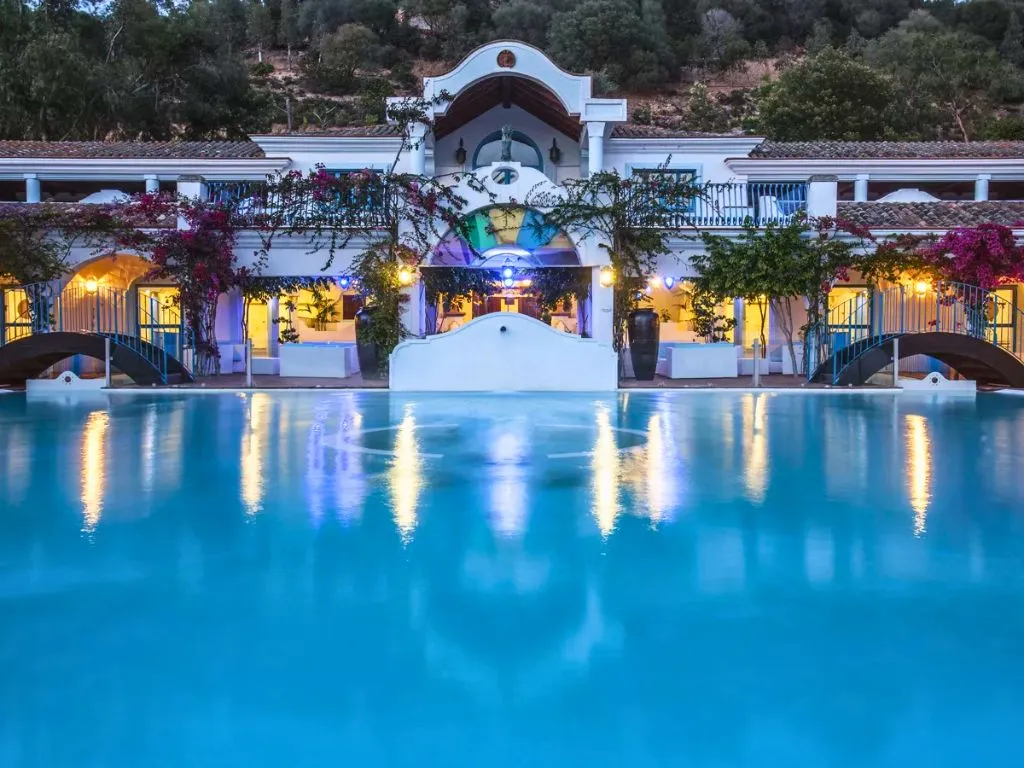 Edificio in stile mediterraneo illuminato di sera riflesso nella piscina