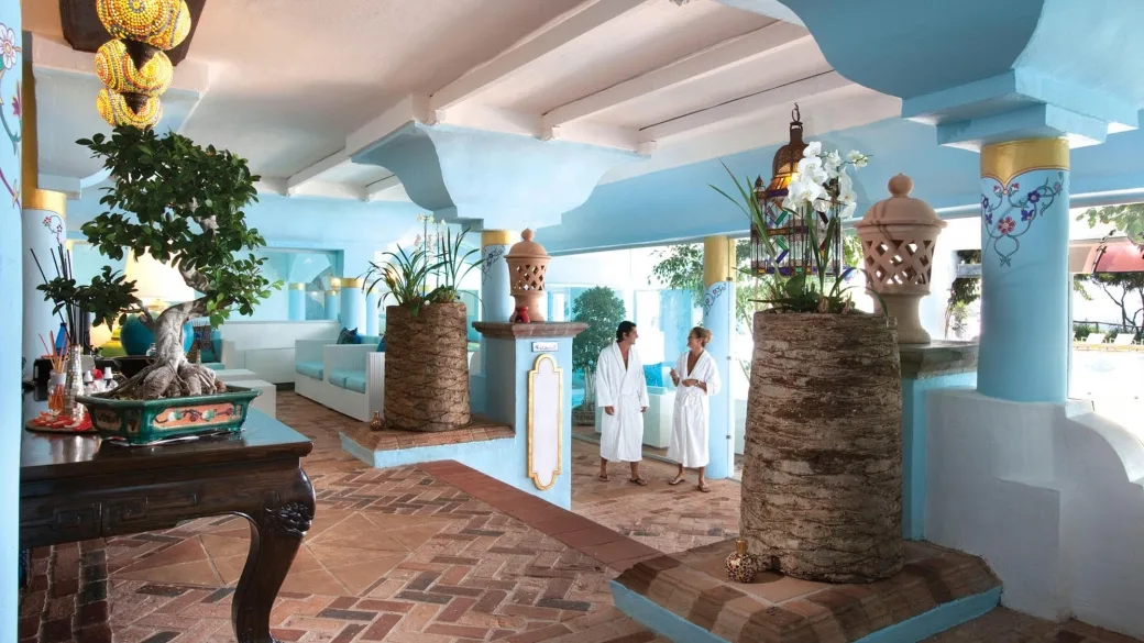 Hall in stile mediterraneo con colonne azzurre, piante e arredi tradizionali