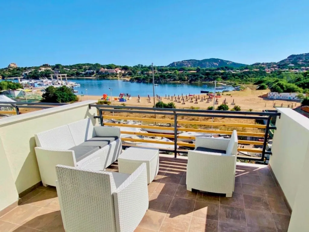Terrazza con divani in rattan e vista sulla spiaggia e il porto