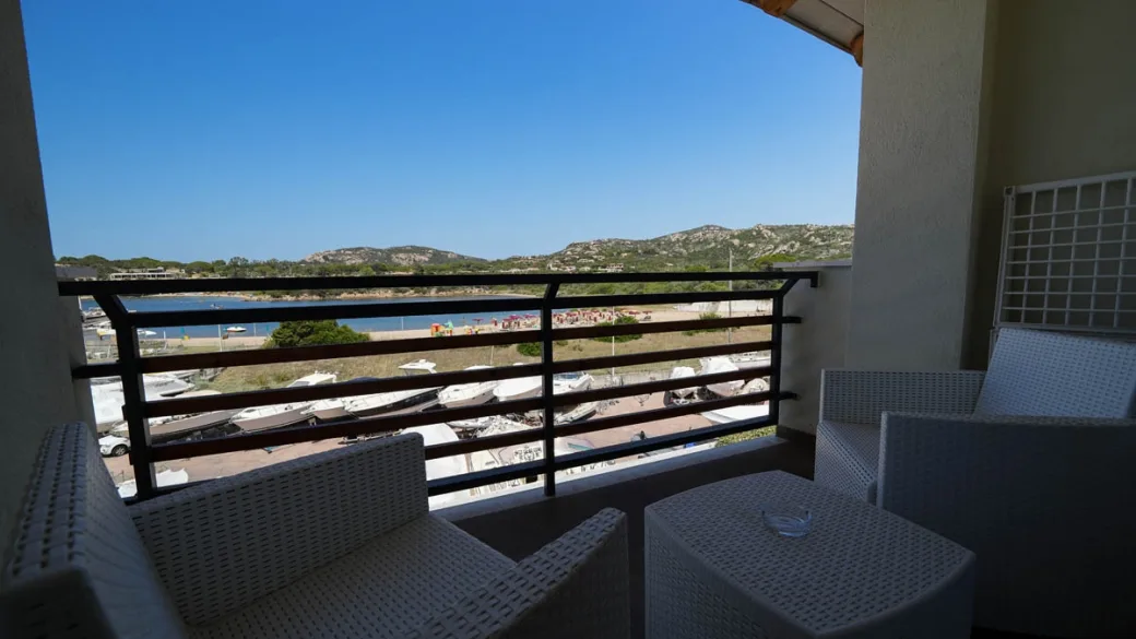 Balcone con poltroncine in rattan e vista sulla spiaggia e il porto
